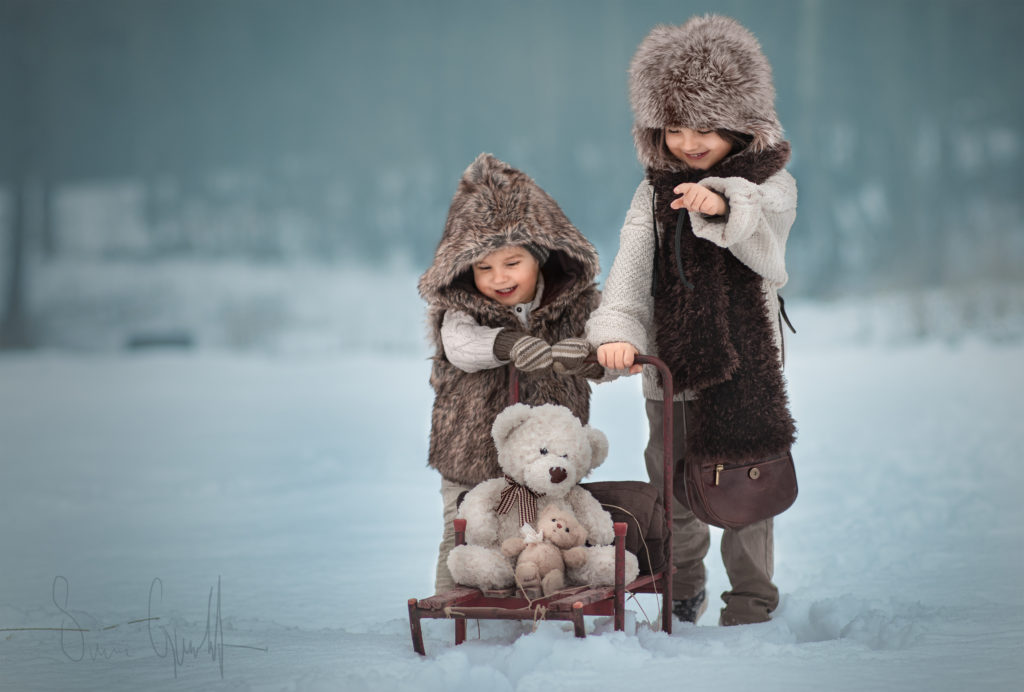 Klä er rätt för utomhusfotografering under höst & vinter. Två barn klädda i lurviga, beige kläder i ett vinterlandskap