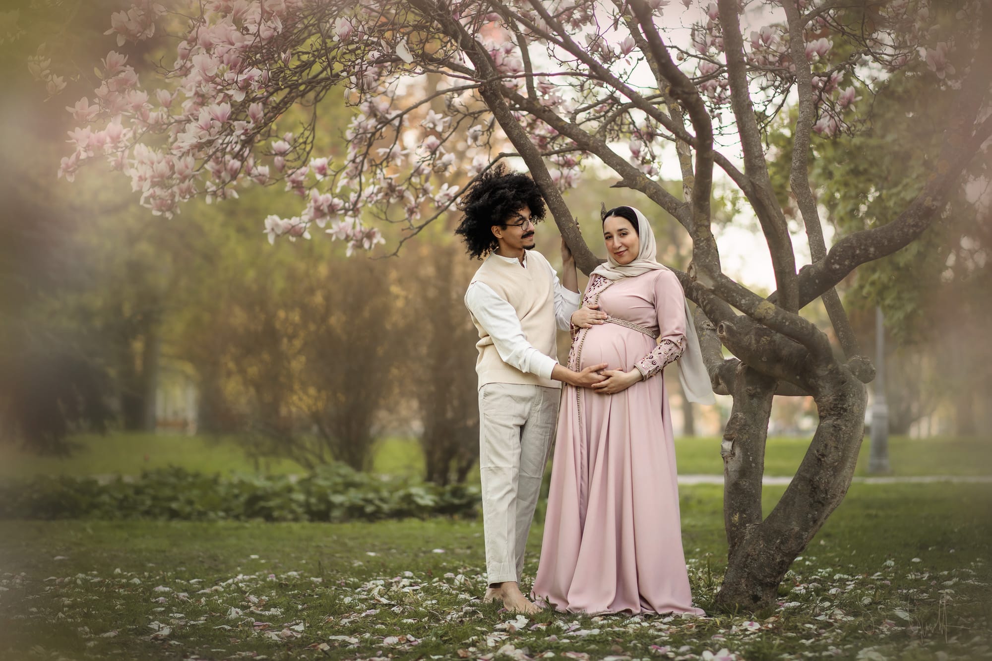 Gravidfotografering av ett par under ett blommande magnoliaträd i Vasaparken i Västerås.