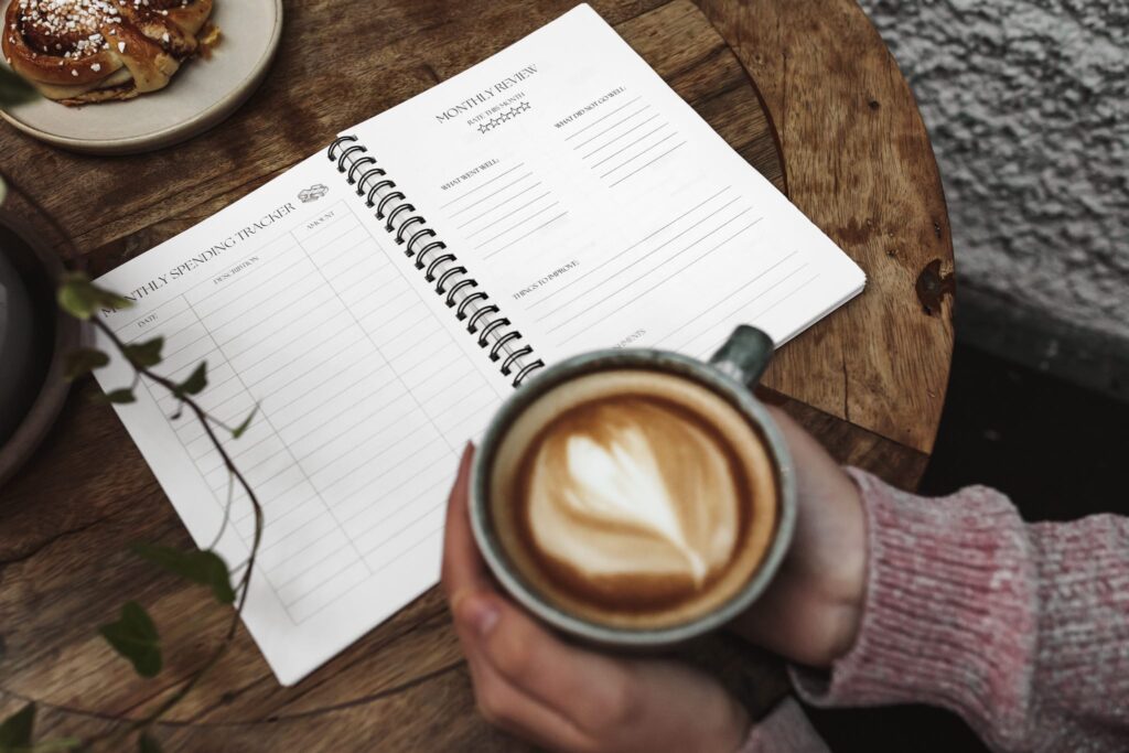 Uppifrån vy av ett café med händer som håller en kaffekopp och en kalender på bordet, vilket skapar en varm och inbjudande atmosfär.