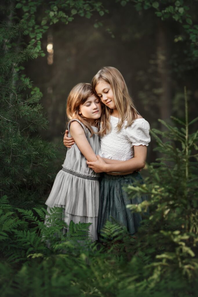 Syskonfotografering i naturen – två flickor kramas under barnfotografering i skogen